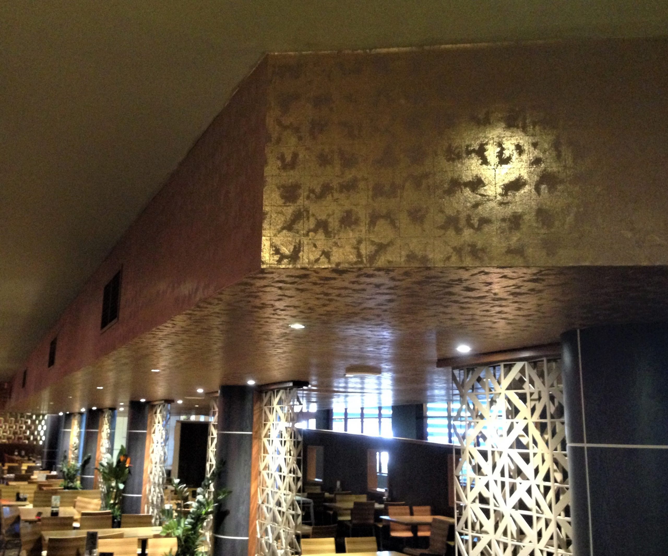 Gold wallpaper installed to a ceiling coffer in a restaurant