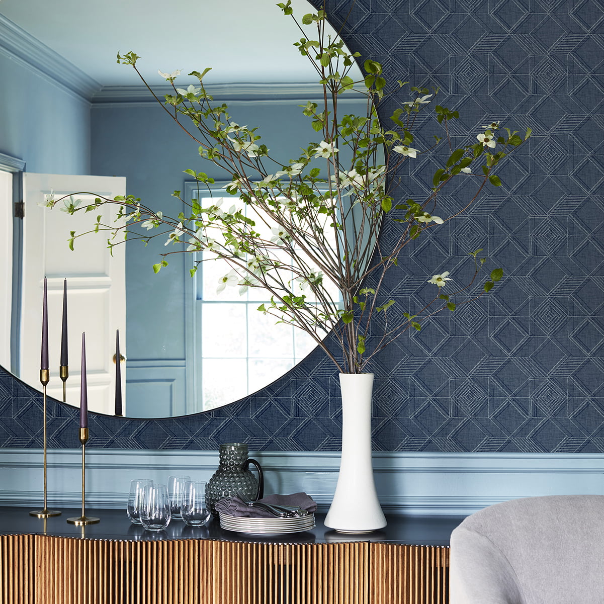blue geometric wallpaper in a living space with a buffet unt and vase and mirror decorating