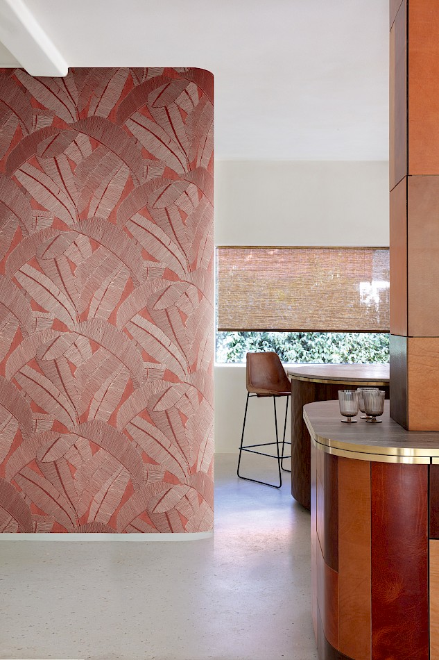 Curved wall with Banyan Amberglow red wallpaper of oversized leaves